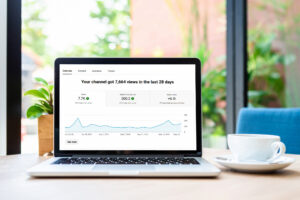 In a bright home office, a laptop screen displays rising YouTube channel analytics.
