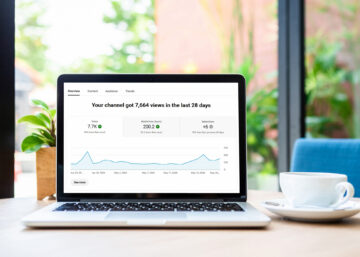 In a bright home office, a laptop screen displays rising YouTube channel analytics.