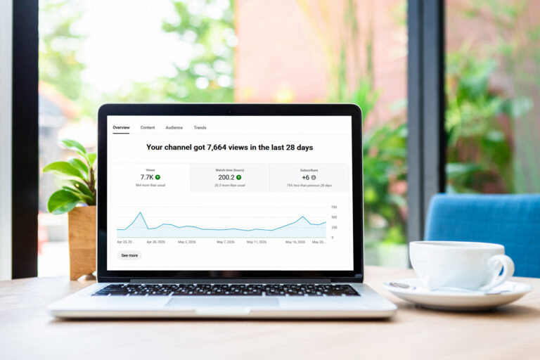 In a bright home office, a laptop screen displays rising YouTube channel analytics.